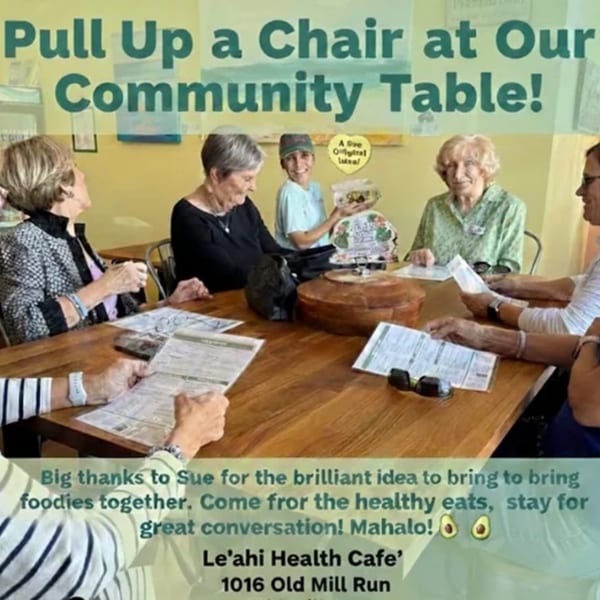 Five people, including a young boy, sit around a wooden table with menus at Leahi Health Cafe.