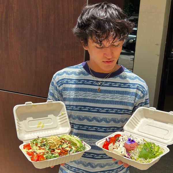 A person holding two open to-go containers filled with colorful, healthy Leahi Health salads.